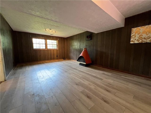 2065 Sandgate Cir, Atlanta, GA 30349 - spare room featuring light wood-style flooring, wood walls, a textured ceiling, and baseboards
