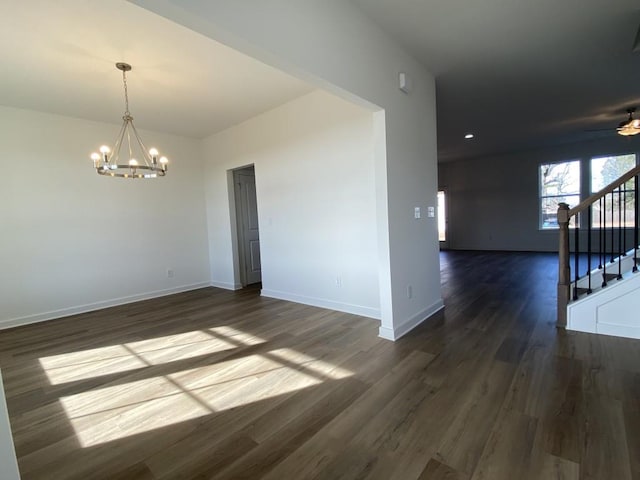 unfurnished room with ceiling fan with notable chandelier and dark wood-type flooring