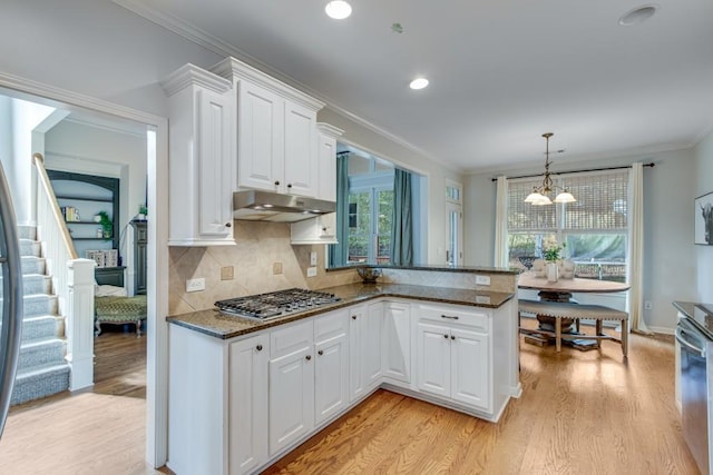 kitchen featuring hanging light fixtures, ornamental molding, kitchen peninsula, stainless steel appliances, and white cabinets