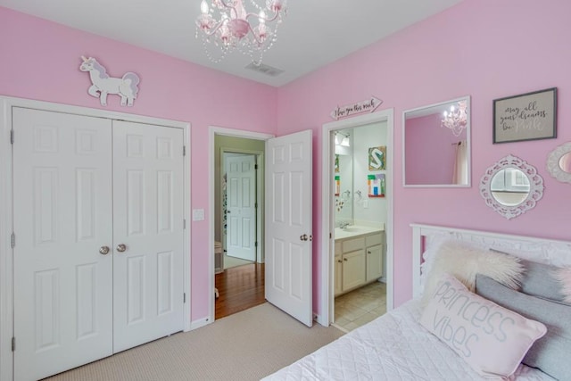 bedroom with sink, ensuite bath, a chandelier, light carpet, and a closet