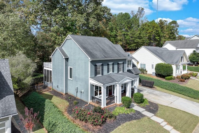 view of front of home with a balcony, covered porch, and a front lawn