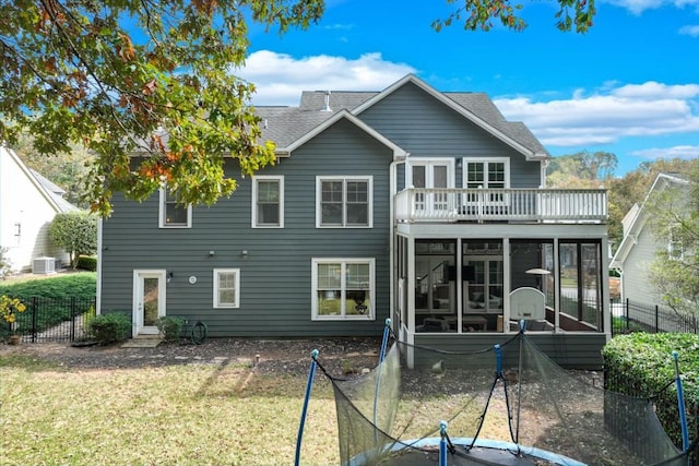 rear view of house with a balcony, a sunroom, central AC unit, and a lawn