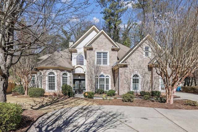 view of front facade featuring french doors, brick siding, and a chimney