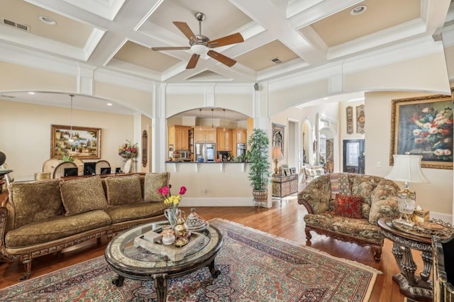 living room with coffered ceiling, arched walkways, visible vents, and wood finished floors