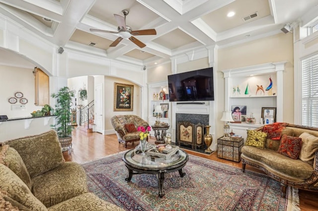 living room featuring a premium fireplace, arched walkways, and wood finished floors