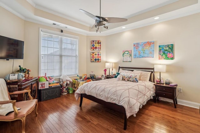 bedroom with crown molding, a raised ceiling, wood-type flooring, a ceiling fan, and baseboards