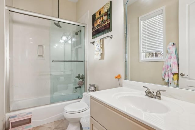 bathroom featuring toilet, vanity, combined bath / shower with glass door, and tile patterned floors