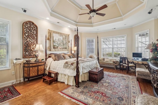 bedroom featuring ornamental molding, a tray ceiling, baseboards, and wood finished floors