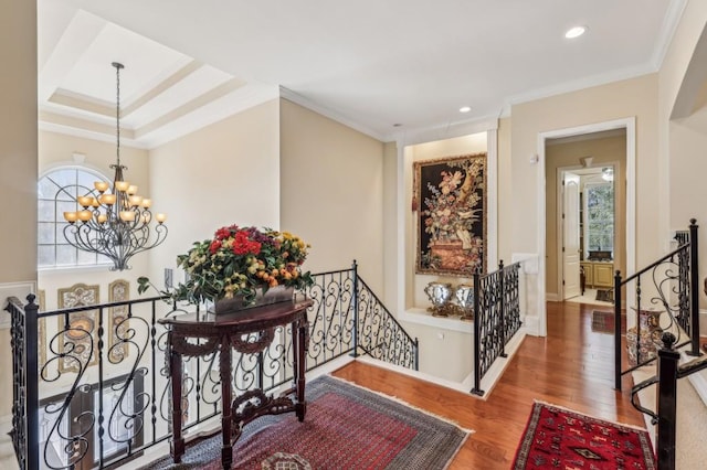 corridor featuring a wealth of natural light, ornamental molding, wood finished floors, and an upstairs landing