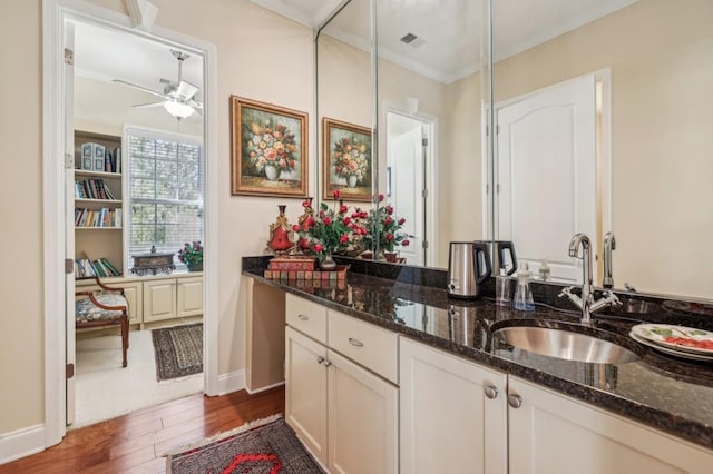 bathroom featuring ceiling fan, wood finished floors, visible vents, vanity, and ornamental molding