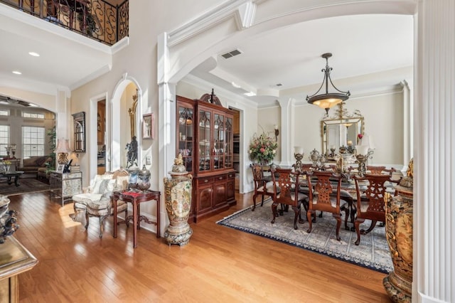 dining area with visible vents, arched walkways, hardwood / wood-style flooring, crown molding, and recessed lighting