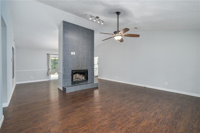 unfurnished living room with lofted ceiling, dark wood-type flooring, a textured ceiling, and a tile fireplace