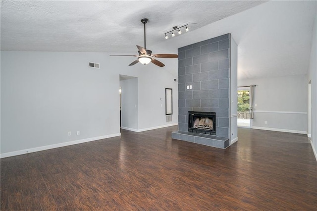 unfurnished living room featuring dark hardwood / wood-style flooring, ceiling fan, a textured ceiling, vaulted ceiling, and a fireplace