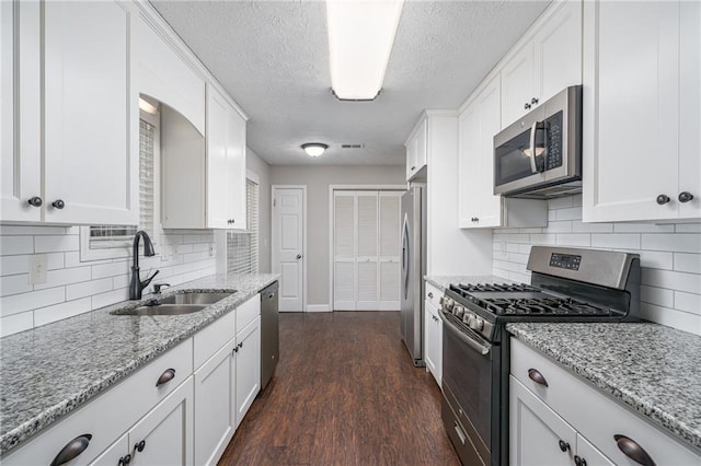 kitchen with appliances with stainless steel finishes, white cabinets, sink, and dark wood-type flooring