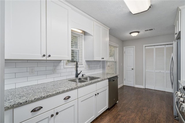 kitchen featuring sink, white cabinetry, appliances with stainless steel finishes, light stone counters, and dark hardwood / wood-style flooring