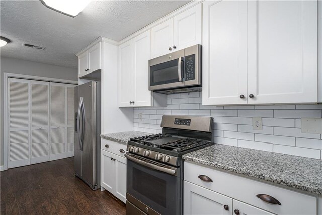 kitchen featuring decorative backsplash, dark wood-type flooring, stainless steel appliances, white cabinetry, and light stone counters