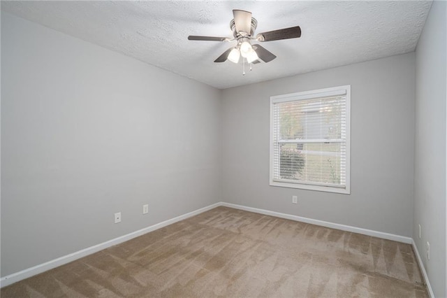 empty room with a textured ceiling, light colored carpet, and ceiling fan