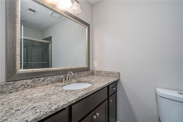 bathroom featuring vanity, a shower with shower door, a textured ceiling, and toilet