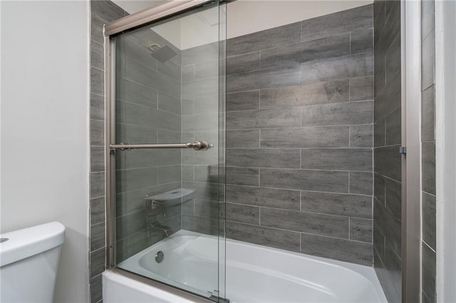 bathroom with toilet and combined bath / shower with glass door