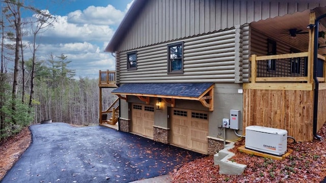 view of side of property with a garage, driveway, ceiling fan, and log siding