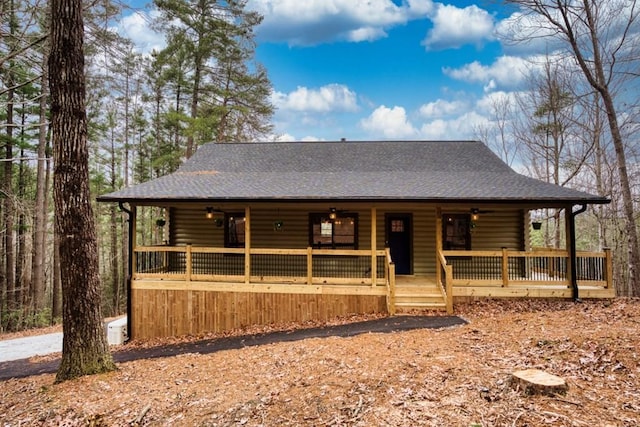 view of front of home featuring covered porch, a shingled roof, and log exterior