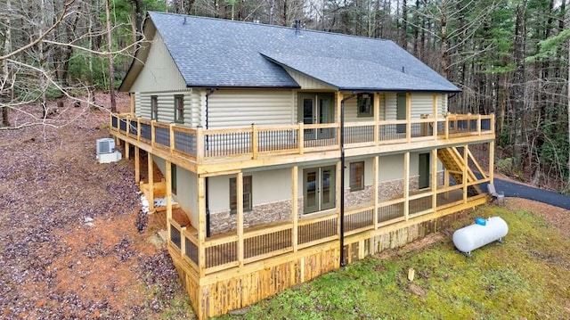 back of house with central air condition unit, a wooden deck, and roof with shingles