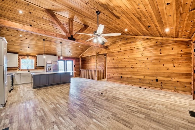 kitchen featuring lofted ceiling, light wood-style flooring, wood walls, a sink, and stainless steel fridge with ice dispenser