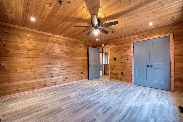 unfurnished bedroom with wooden ceiling, a closet, wood finished floors, and wood walls