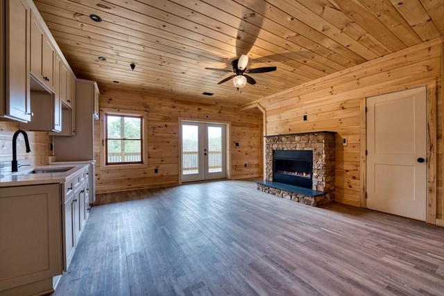 interior space with a stone fireplace, wooden ceiling, wood finished floors, a sink, and light countertops