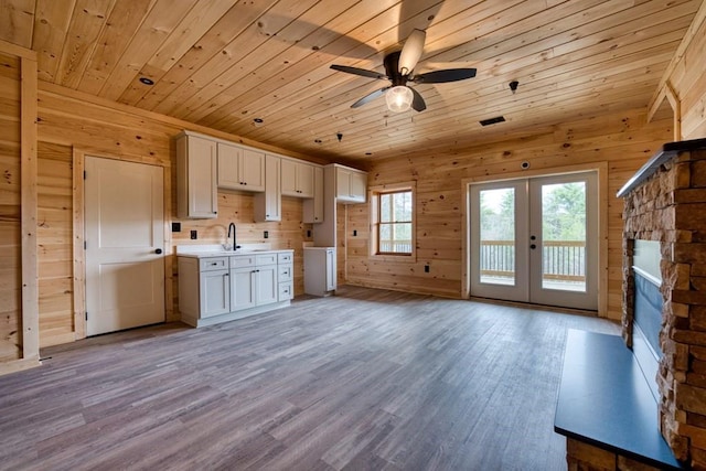 interior space featuring wooden ceiling, wood finished floors, french doors, wood walls, and white cabinetry