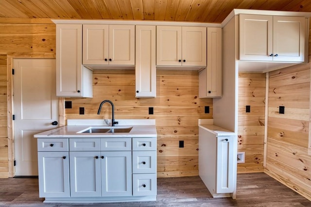 kitchen featuring dark wood-style floors, light countertops, a sink, wood walls, and wooden ceiling