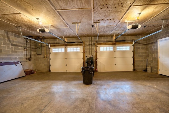 parking deck with concrete block wall, electric panel, and a garage door opener