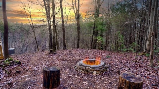 view of yard featuring a fire pit and a wooded view