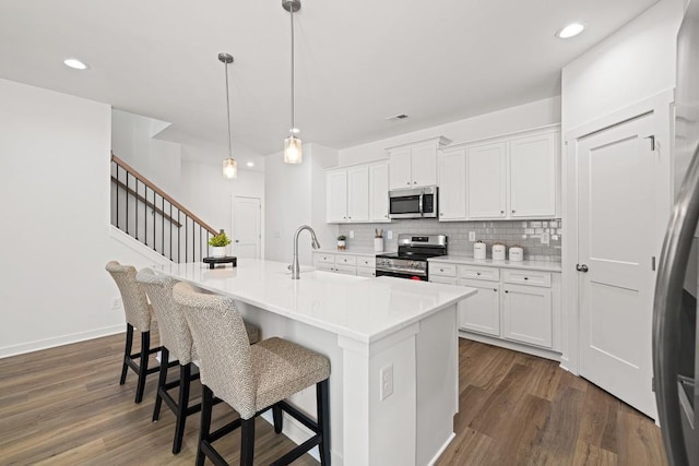 kitchen featuring a sink, a kitchen breakfast bar, stainless steel appliances, decorative backsplash, and dark wood-style flooring