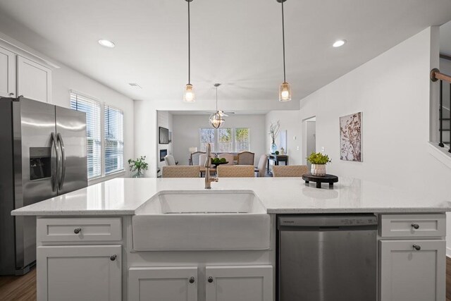 kitchen featuring a sink, appliances with stainless steel finishes, open floor plan, and a healthy amount of sunlight