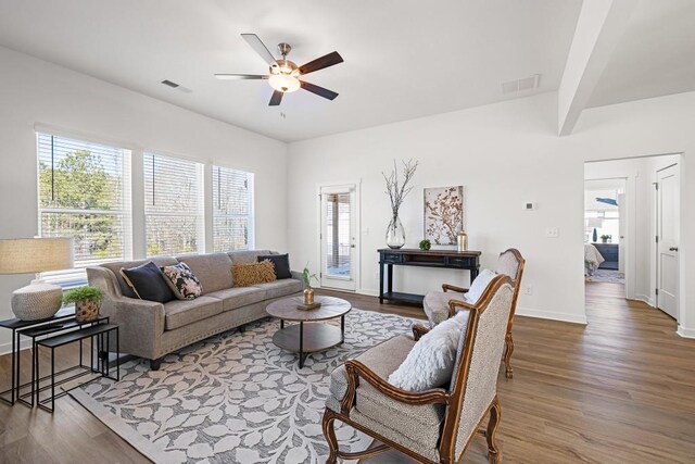 living area featuring visible vents, a ceiling fan, baseboards, and wood finished floors