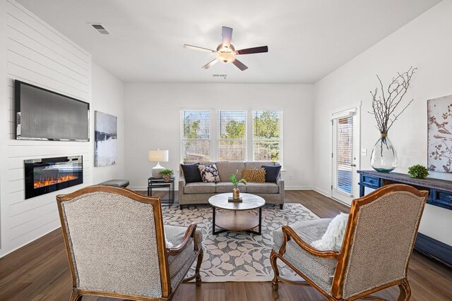 living room with a ceiling fan, baseboards, wood finished floors, visible vents, and a large fireplace