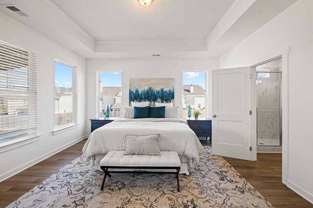 bedroom with a tray ceiling, visible vents, dark wood-style flooring, and baseboards