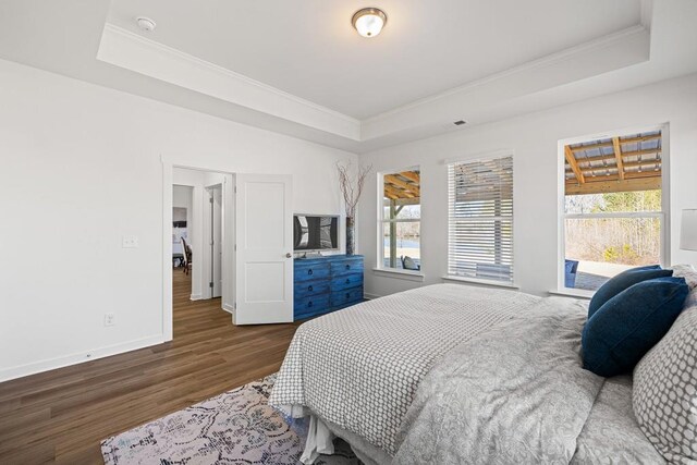 bedroom featuring baseboards, crown molding, a tray ceiling, and wood finished floors