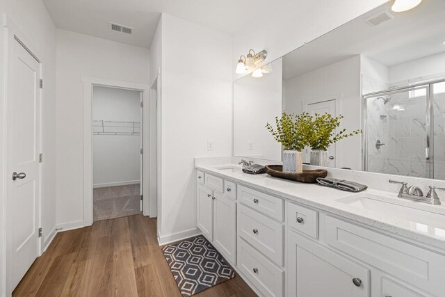 bathroom featuring a sink, visible vents, a marble finish shower, and a walk in closet