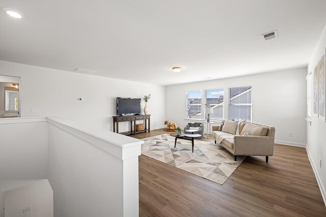 living area with visible vents, baseboards, and wood finished floors