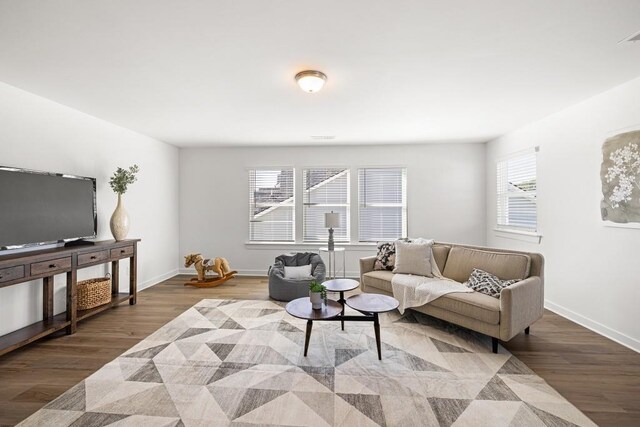 living area with visible vents, wood finished floors, baseboards, and a healthy amount of sunlight