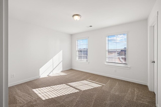 carpeted empty room featuring visible vents and baseboards