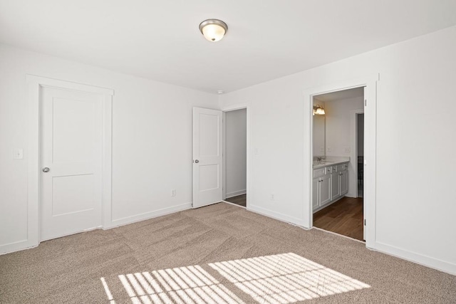 unfurnished bedroom featuring connected bathroom, baseboards, and carpet floors