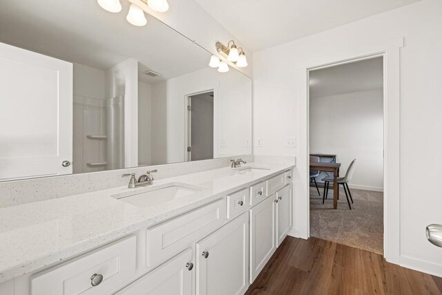 bathroom featuring double vanity, wood finished floors, baseboards, and a sink