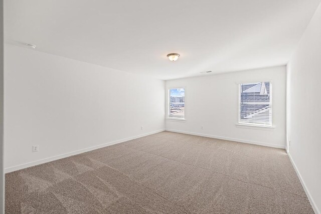 carpeted empty room featuring baseboards