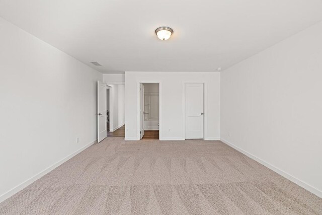 unfurnished bedroom with visible vents, baseboards, carpet, and ensuite bath