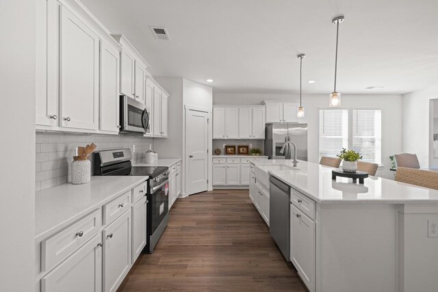 kitchen with dark wood-type flooring, white cabinets, light countertops, and appliances with stainless steel finishes