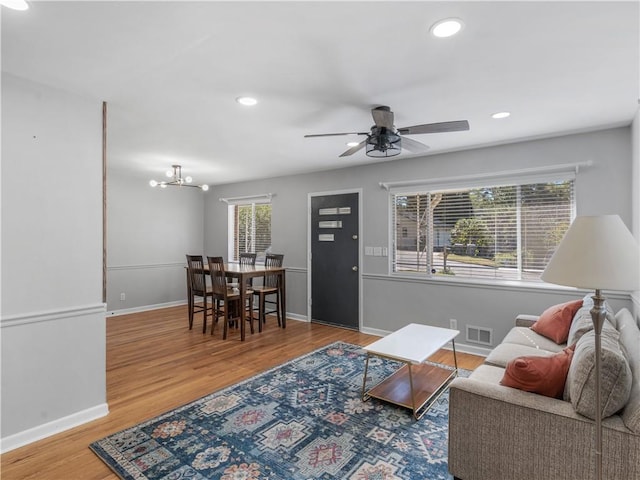 living room with wood-type flooring and ceiling fan with notable chandelier