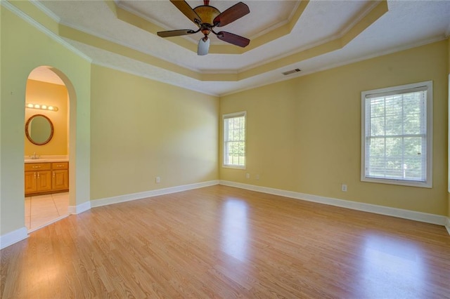 172 Lakeview Dr, Newborn, GA 30056 - empty room featuring a tray ceiling, crown molding, ceiling fan, light wood-style floors, and arched walkways
